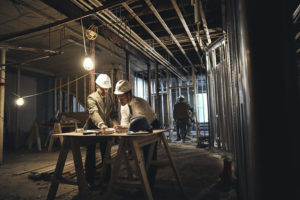 Construction site, two adults showing reviewing plans.